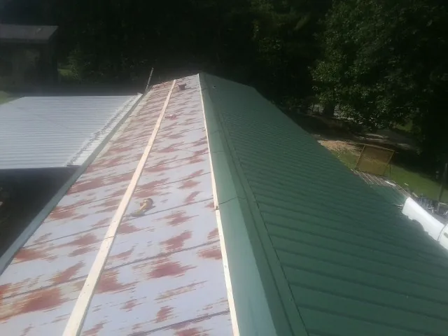 Old rusted panels beside newly installed green metal roofing — Wind Damage Roof Repair by Roofing Brothers in Cadiz