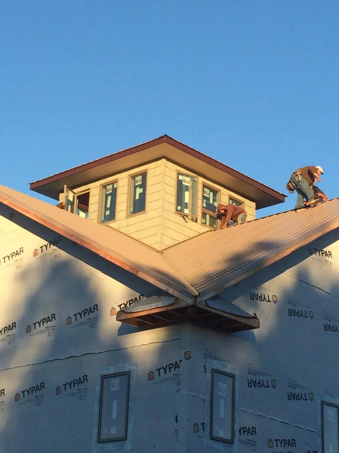 Roofers working around a rooftop cupola on a new metal roof at sunset — Roof Waterproofing in Cadiz by Roofing Brothers